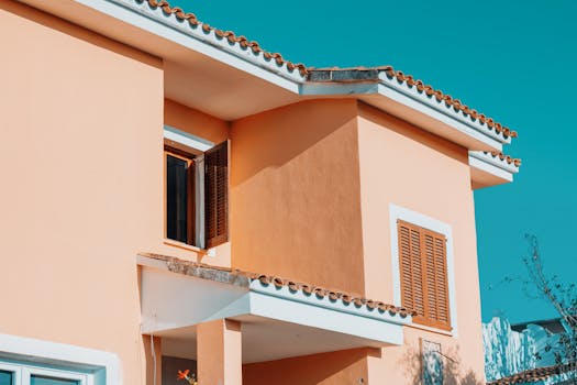 Middle section of a Mediterranean style house with orange hues against a bright blue sky in Spain.